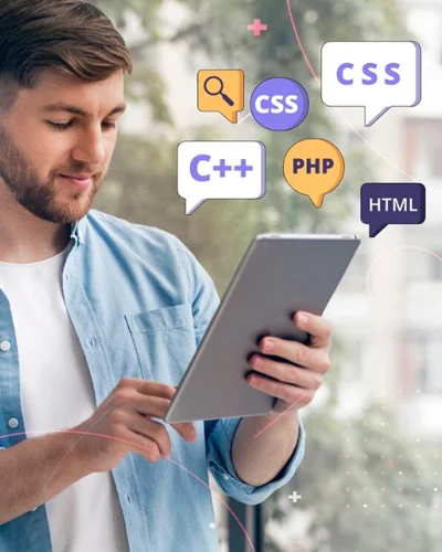 Joven desarrollador consultando su tablet mientras burbujas flotantes muestran iconos de CSS, HTML, PHP y C++